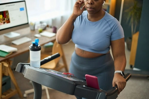 A woman on call in a treadmill in the morning — Walking Pads or Treadmills